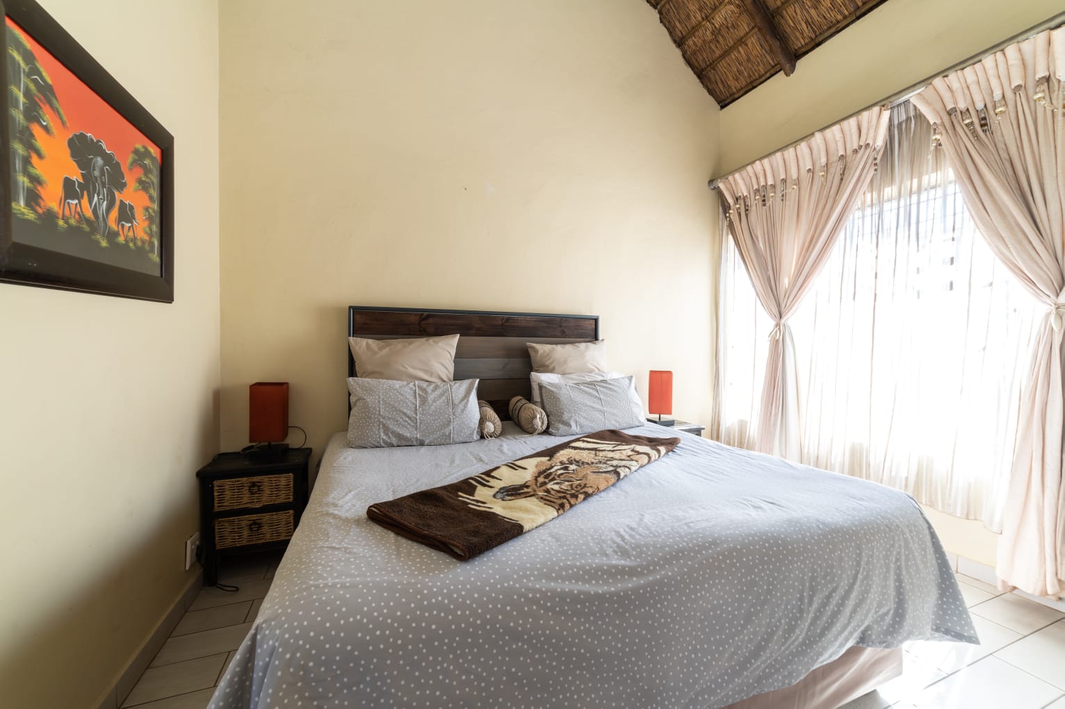 Comfortable guest accommodation at Thatch Haven featuring African-inspired wall art and a rustic headboard.