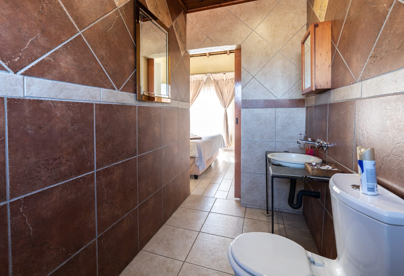 Modern tiled bathroom with a view leading into the bright guest bedroom at Thatch Haven.
