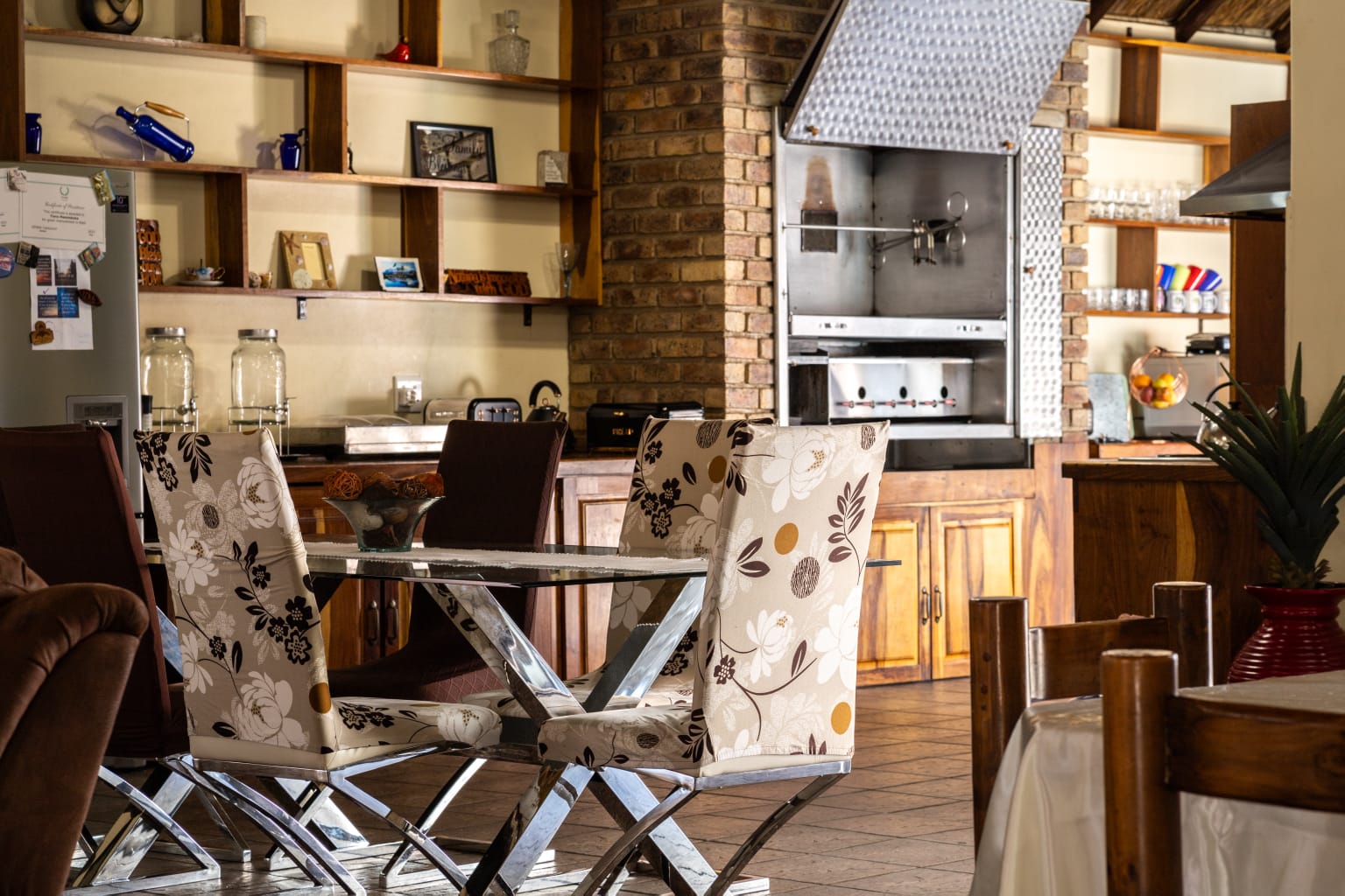 Outdoor entertainment area with a braai stand and seating, showcasing the brickwork and thatch architecture.