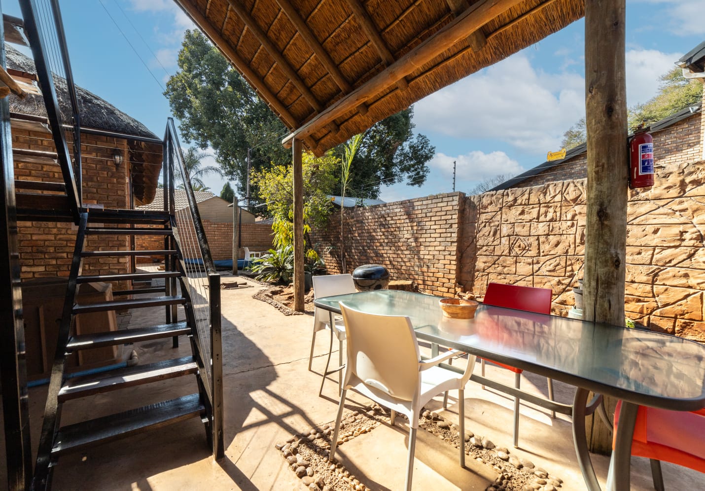 Relaxing outdoor patio area with a glass table and seating, ideal for enjoying the South African weather.