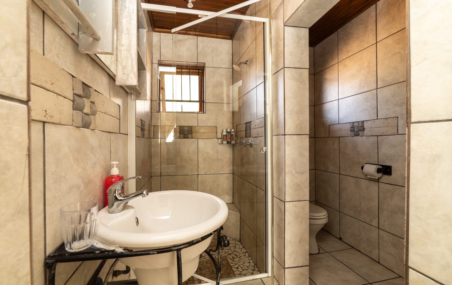 Modern tiled bathroom with a view leading into the bright guest bedroom at Thatch Haven.