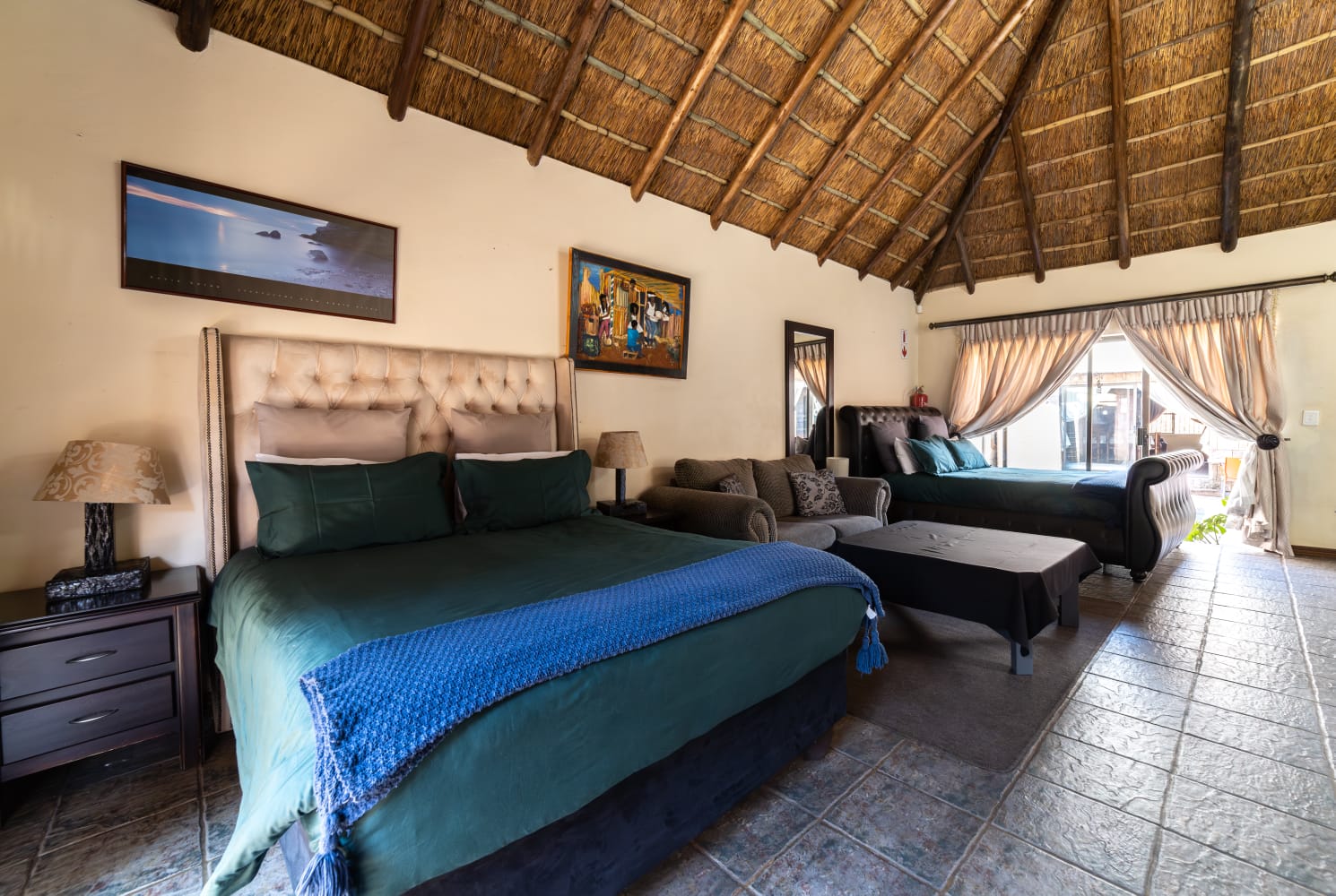 Comfortable guest accommodation at Thatch Haven featuring African-inspired wall art and a rustic headboard.