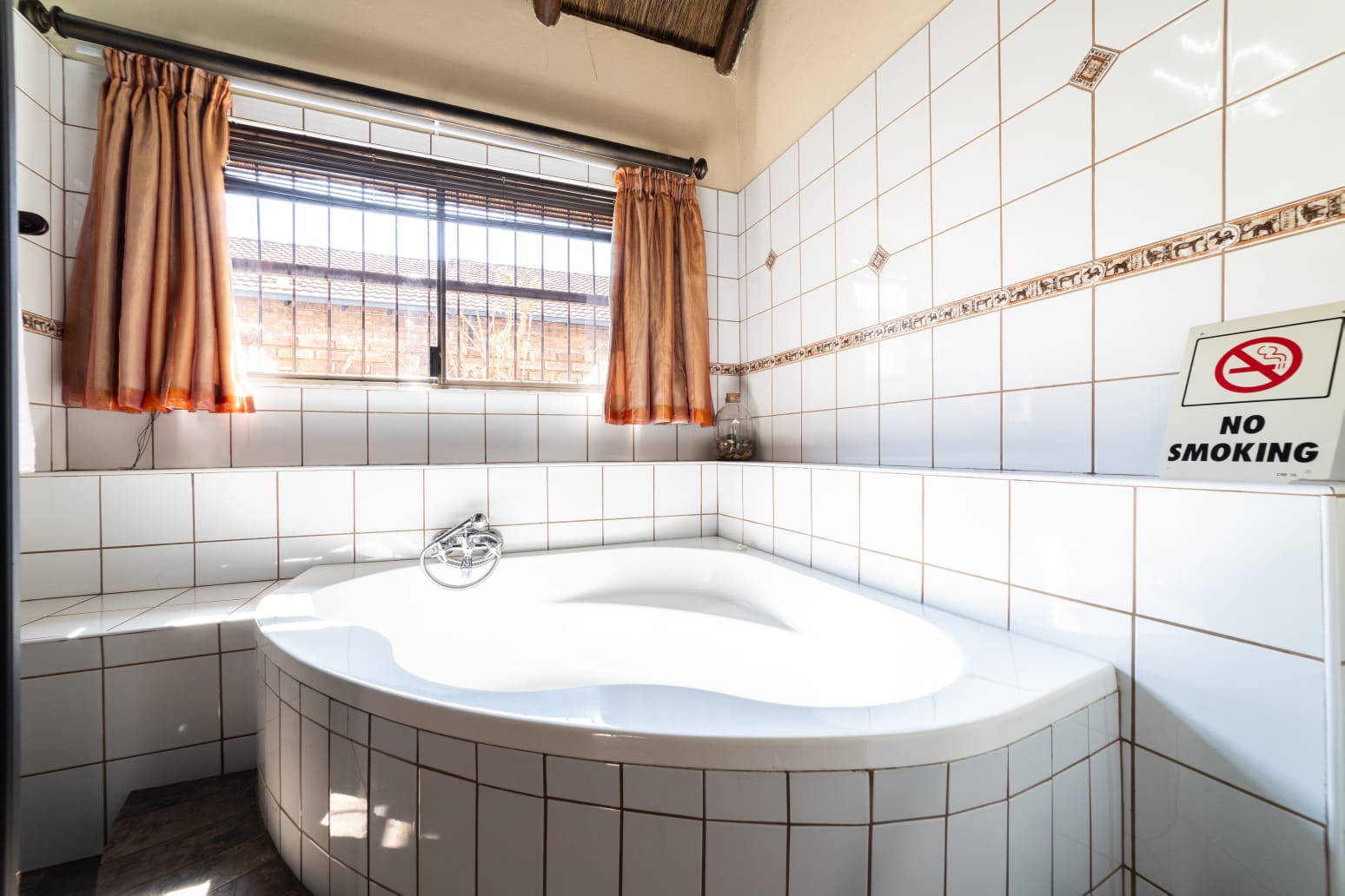Modern tiled bathroom with a view leading into the bright guest bedroom at Thatch Haven.